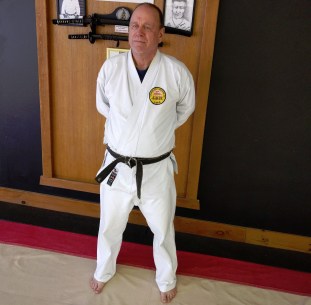 Sensei Steve Jansen standing in white karate uniform and black belt.
